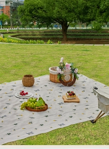 Detail of outdoor picnic mat with vintage floral pattern on green grass lawn