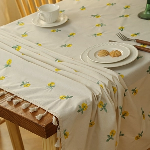 Beige rectangular tablecloth with yellow floral embroidery and white fringe edges