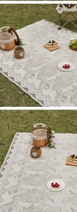Detail of tulip printed picnic mat with delicate lace trim on green grass lawn