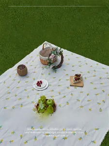 Detail of sunflower embroidered waterproof picnic mat with fringe edges on green grass