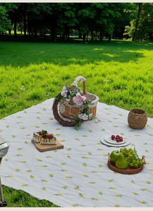 Outdoor picnic mat detail with yellow flower pattern, woven basket and fresh fruits