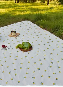 Detail of floral picnic mat with yellow flowers, fringe edges and outdoor setup
