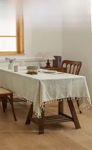 Detail of light green slub linen tablecloth featuring elegant white tassel edges and texture