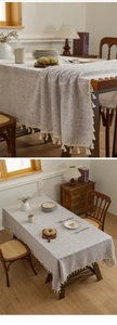 Close-up of linen table cloth featuring white tassel fringe on natural wooden table
