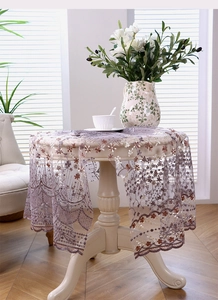 Gros plan sur une nappe en dentelle lavande avec broderie florale sur table blanche