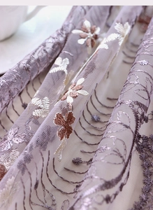 Détail d'une nappe en dentelle lavande avec broderie florale 3D et bordures festonnées