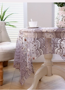 Détail d'une nappe en dentelle lavande avec broderies florales et bordures festonnées