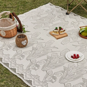 Outdoor beige picnic mat with tulip knit pattern and elegant lace border on green grass