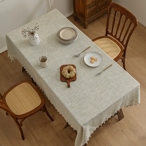 Nappe japonaise en lin vert sauge avec pompons blancs décoratifs sur une table bois