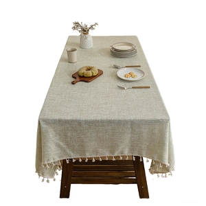 Modern light green linen tablecloth with white tassels on a rectangular wooden dining table