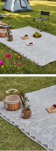 Detail of light grey outdoor picnic mat with floral lace pattern on a sunny lawn