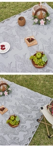 Detail of grey jacquard picnic mat with tulip patterns and decorative lace edges