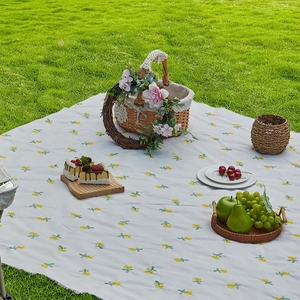 Waterproof outdoor picnic mat with yellow floral pattern on green grass background