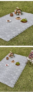 Detailed view of intricate floral lace patterns and scalloped edges on light grey picnic mat