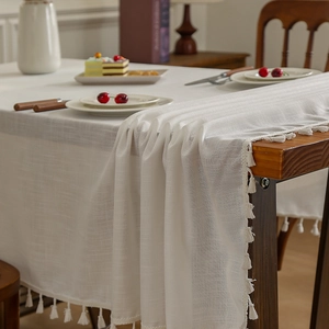 Nappe japonaise en lin blanc avec bordures à pompons sur une table en bois massif