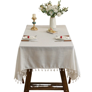 Nappe japonaise en lin crème uni avec pompons élégants sur une table en bois massif