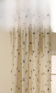 Détail du rideau en lin avec broderie de fleurs jaunes et bordure décorative à pompons