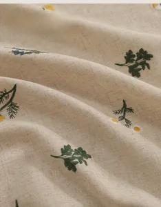 Détail du tissu en lin avec broderie de marguerites et texture tissée