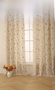 Détail de rideaux en lin avec broderie d'épis et bordure à pompons blancs décoratifs