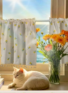 Detail of cream cafe curtain with yellow flower embroidery and white fringe tassels