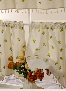 Detail of floral embroidery and beige tassels on waterproof kitchen cafe curtain