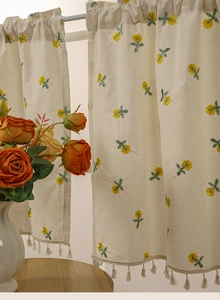 Close-up of beige linen coffee curtain with yellow flower embroidery and tassel fringe