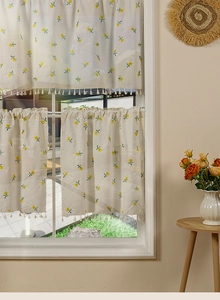 Detail of cream cafe curtains with yellow floral embroidery and beige tassel fringes
