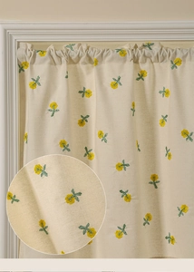 Close-up of beige kitchen curtain with yellow flower embroidery and linen texture details