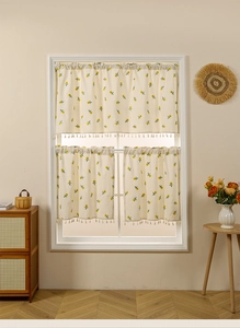 Detail of floral embroidered kitchen curtains with fringe trim on white window frame
