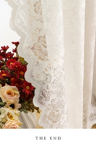 Detailed close-up of white floral lace curtain fabric with scalloped embroidery edges