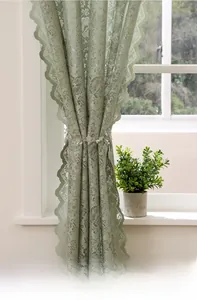 Detail of light green floral lace curtain with scalloped edges and elegant flower tieback