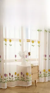 Detail of delicate tulip floral embroidery on white sheer curtain with wavy scalloped edge