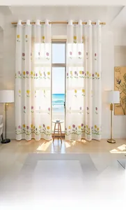 Detail of tulip embroidery on sheer white curtains with metal eyelet rings in a bright room