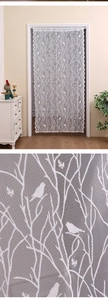 Close-up of white lace curtain featuring delicate bird and branch jacquard patterns