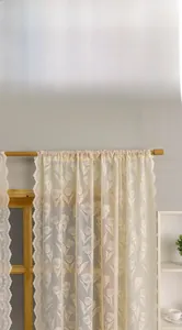 Detail of cream tulip lace curtain with scalloped edges and floral embroidery