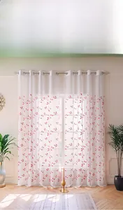 Detail of white sheer curtain with red leaf embroidery and metal grommet top headers