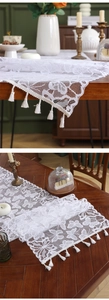 Close-up of white lace table runner featuring butterfly embroidery and fringe tassels