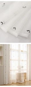 Close-up of white sheer curtain fabric featuring delicate black cat embroidery details