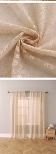 Detailed close-up of cream floral lace curtain fabric and warm home interior setting