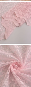 Macro detail of delicate pink floral lace embroidery on semi-transparent mesh curtain fabric