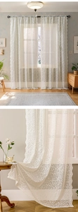 Close-up of white lace curtain featuring delicate floral embroidery and scalloped edges
