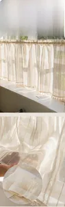 Detailed view of beige semi-transparent cafe curtain with vertical stripes and tassel fringe