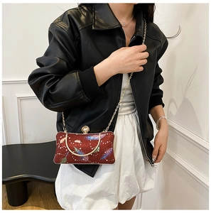 Detalle del bolso de noche rojo con lentejuelas plumas y asa de anillo dorada
