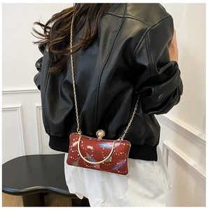 Detalle del bolso de noche rojo brillante con plumas y elegante asa de anillo oro
