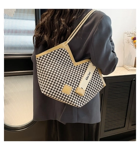 Detail of houndstooth tote bag with V-cut edge and wide fabric strap shown on shoulder