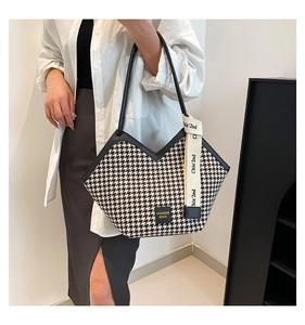 Detail of houndstooth tote bag featuring a V-shaped top and decorative ribbon detail