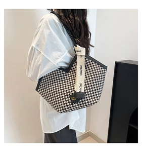 Detail of black and white houndstooth tote bag with a branded lettered shoulder strap