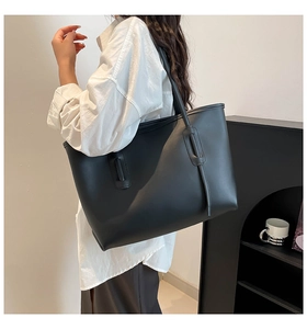 Detail of a large black leather tote bag with smooth finish and elegant strap loops