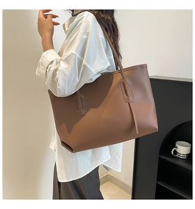 Detail view of brown leather tote bag with decorative side stitching and long strap