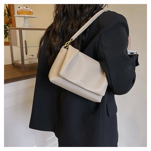 Chic light beige litchi leather shoulder bag with gold hardware worn by a model